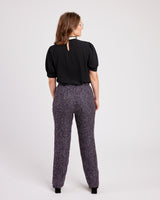 Woman wearing a black blouse and patterned pants on a white background. These pants are the Meriam Trousers sewing pattern from Cashmerette.