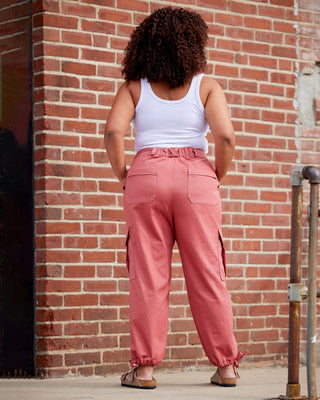 Person wearing a white tank top and pink pants standing against a brick wall. These pants are the Esmond Cargo Pants sewing pattern from Cashmerette.