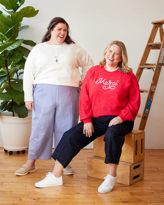 Two women standing in a room with a plant and wooden ladder. These pants are the Vinton Pants sewing pattern from Cashmerette.