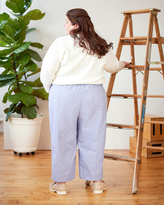 Person standing next to a wooden ladder in a room with a plant and boxes. These pants are the Vinton Pants sewing pattern from Cashmerette.