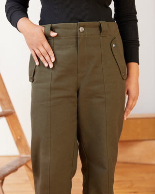 Person wearing olive green pants with a blurred background. These pants are the Vinton Pants sewing pattern from Cashmerette.