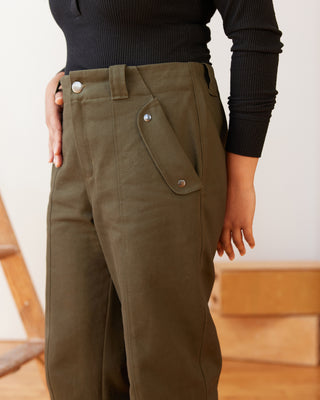 Person wearing olive green pants with a blurred background. These pants are the Vinton Pants sewing pattern from Cashmerette.