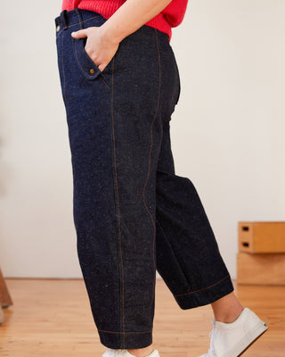 Person wearing dark blue jeans with a red top and white shoes on a light background. These pants are the Vinton Pants sewing pattern from Cashmerette.