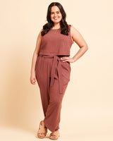 Woman wearing a brown sleeveless top and pants on a beige background. These pants are the Everett Pants & Shorts sewing pattern from Cashmerette.