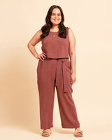 Woman wearing a brown top and brown pants in front of a yellow background. These shorts are the Everett Pants & Shorts sewing pattern from Cashmerette.