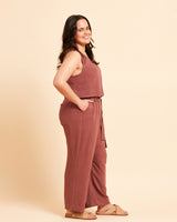 Woman wearing a brown sleeveless top and wide-leg pants on a beige background. These pants are the Everett Pants & Shorts sewing pattern from Cashmerette.