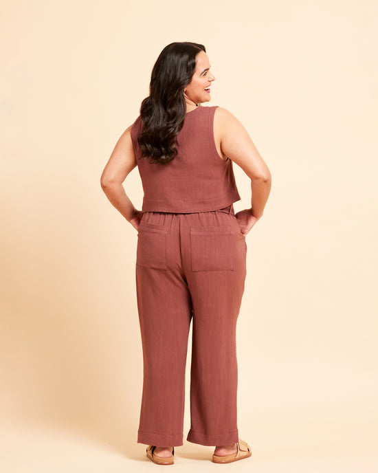 Woman wearing a brown sleeveless top and pants against a beige background. These pants are the Everett Pants & Shorts sewing pattern from Cashmerette.