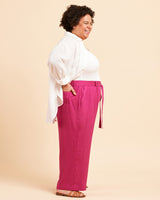 Woman wearing a white blouse and pink pants on a beige background. These pants are the Everett Pants & Shorts sewing pattern from Cashmerette.