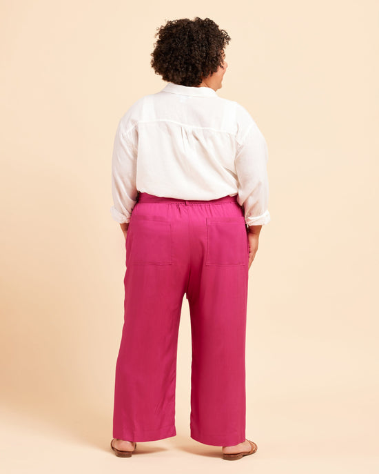 Person wearing a white shirt and pink pants on a beige background. These pants are the Everett Pants & Shorts sewing pattern from Cashmerette.