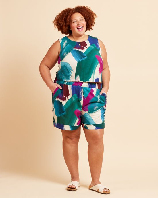 Woman wearing a colorful sleeveless top and shorts set on a beige background. These shorts are the Everett Pants & Shorts sewing pattern from Cashmerette.