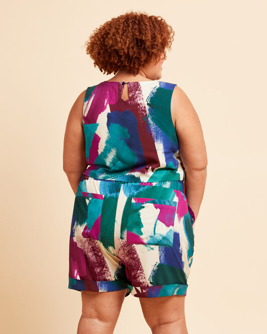 Person wearing a colorful sleeveless top and shorts set on a beige background. These shorts are the Everett Pants & Shorts sewing pattern from Cashmerette.