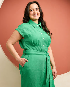 Woman wearing a green dress against a warm-toned background. This is the Roslindale Jumpsuit sewing pattern from Cashmerette.