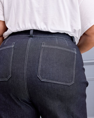 Close-up back view of a person wearing dark indigo denim jeans with white contrast stitching and a white t-shirt. This is the Exeter Jeans sewing pattern from Cashmerette.