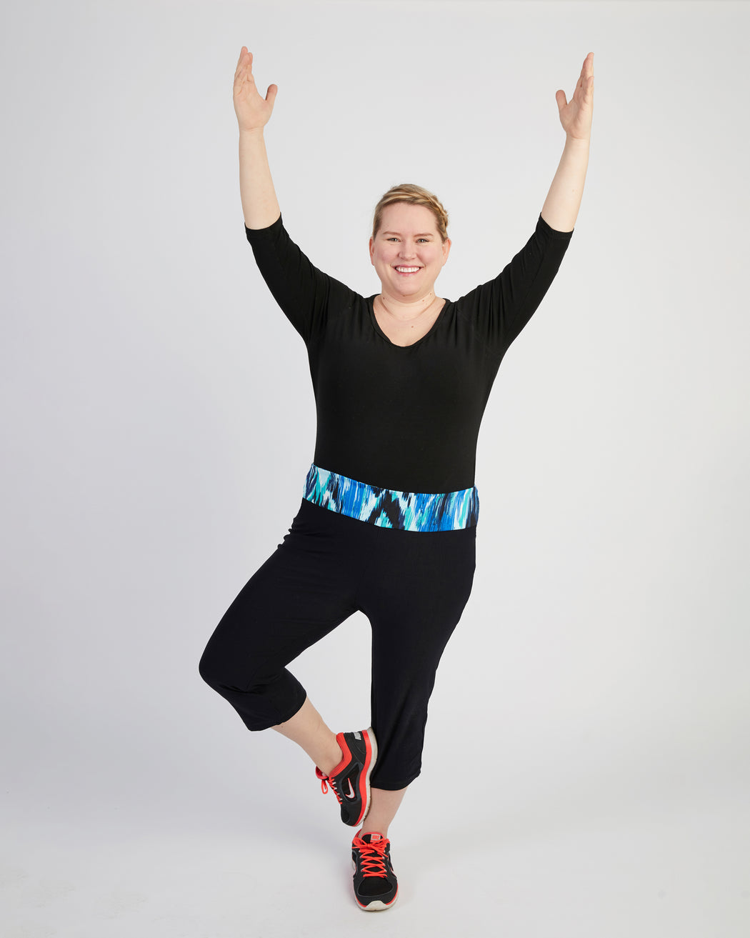 Person wearing a black outfit with a colorful belt on a white background. These leggings are the Belmont Leggings and Yoga Pants sewing pattern from Cashmerette.