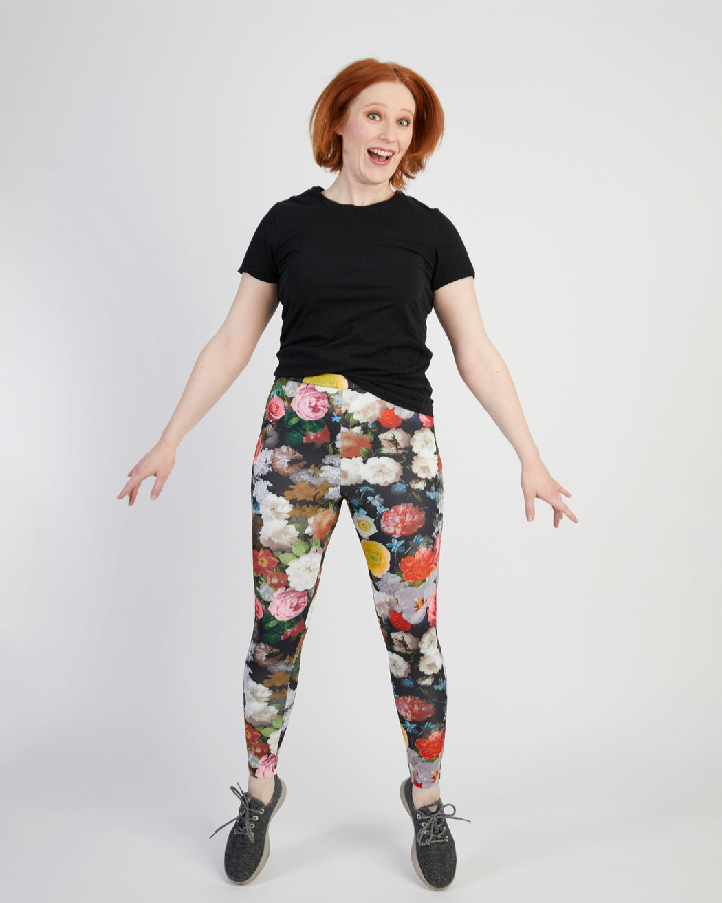 Person wearing a black t-shirt and floral leggings on a white background. These leggings are the Belmont Leggings and Yoga Pants sewing pattern from Cashmerette.