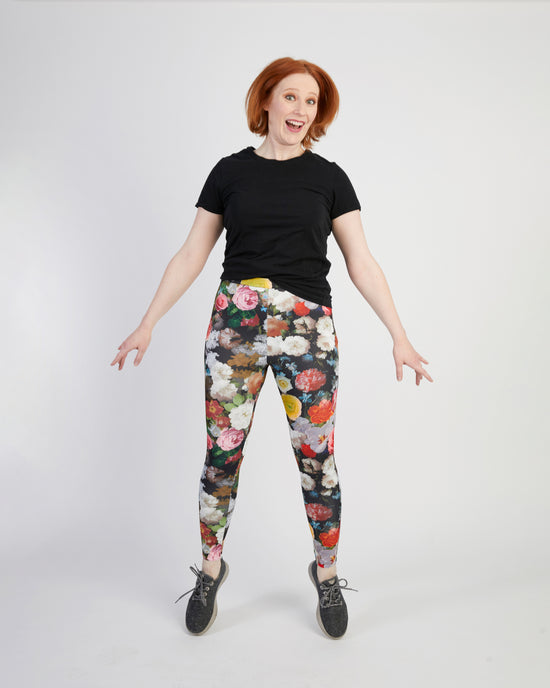 Person wearing a black t-shirt and floral leggings on a white background. These leggings are the Belmont Leggings and Yoga Pants sewing pattern from Cashmerette.