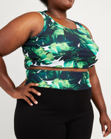 Person wearing a green leaf-patterned top and black pants on a white background. These leggings are the Belmont Leggings and Yoga Pants sewing pattern from Cashmerette.