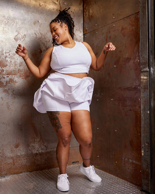 Person wearing a white outfit standing against a textured wall. This skirt is the Wickham Skort sewing pattern from Cashmerette.