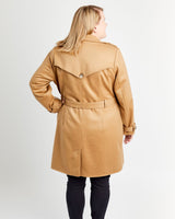 Woman wearing a tan trench coat on a white background. This coat is the Chilton Trench Coat sewing pattern from Cashmerette.