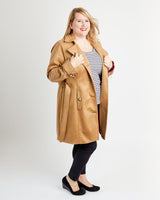 Woman wearing a tan coat over a striped shirt on a white background. This coat is the Chilton Trench Coat sewing pattern from Cashmerette.