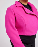Bright pink jacket worn by a person on a light gray background. This biker jacket is the Canton Moto Jacket sewing pattern from Cashmerette.