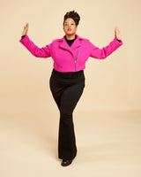 Person wearing a bright pink jacket and black pants on a beige background. This biker jacket is the Canton Moto Jacket sewing pattern from Cashmerette.
