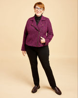 Woman wearing a purple jacket and black pants on a beige background. This biker jacket is the Canton Moto Jacket sewing pattern from Cashmerette.