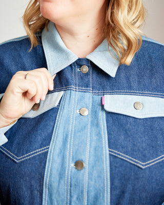 Close-up of a person wearing a blue denim jacket with a light blue shirt underneath. This jacket is the Glover Jean Jacket sewing pattern from Cashmerette.