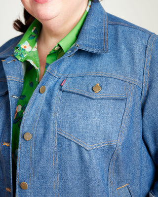 Close-up of a blue denim jacket with a green shirt underneath. This jacket is the Glover Jean Jacket sewing pattern from Cashmerette.