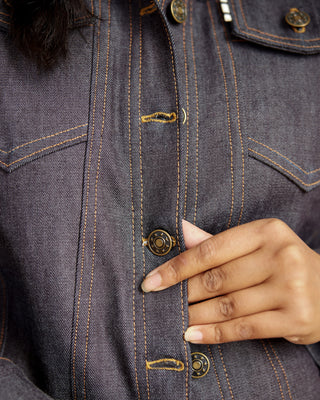 Close-up of a hand pressing a button on a dark denim jacket. This jacket is the Glover Jean Jacket sewing pattern from Cashmerette.