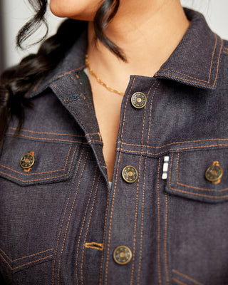 Close-up of a person wearing a dark denim jacket with gold buttons. This jacket is the Glover Jean Jacket sewing pattern from Cashmerette.