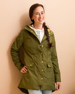 Woman wearing a green jacket against a beige background. This is the Marston Raincoat sewing pattern from Cashmerette Club.