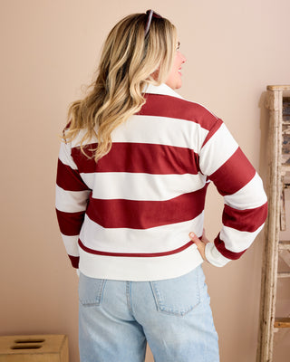 Woman wearing a red and white striped sweater and light blue jeans against a beige wall. This is the Brookhaven Sweatshirt sewing pattern from Cashmerette.