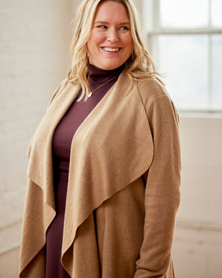 Woman wearing a beige cardigan over a dark top in a bright room. This cardigan is the Westmore Cardigan sewing pattern from Cashmerette.