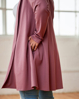 Person wearing a long, mauve cardigan with a blurred background. This cardigan is the Westmore Cardigan sewing pattern from Cashmerette.