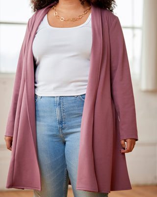 Person wearing a long mauve cardigan over a white top and blue jeans indoors. This cardigan is the Westmore Cardigan sewing pattern from Cashmerette.