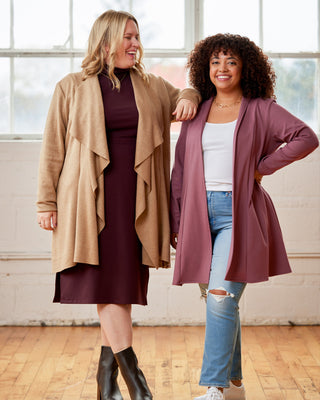 Two women standing together in a room with large windows, wearing long cardigans. This cardigan is the Westmore Cardigan sewing pattern from Cashmerette.