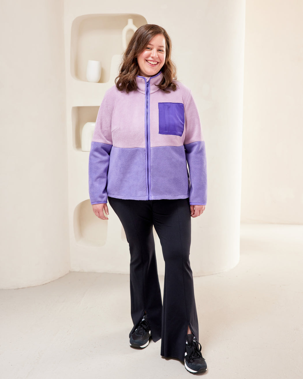 Person wearing a two-tone fleece jacket with a purple pocket on a white background. This jacket is the Hatton Fleece Jacket sewing pattern from Cashmerette.