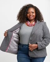 Woman wearing a gray blazer with a red interior lining, standing against a plain background. This blazer is the Auburn Blazer sewing pattern from Cashmerette.
