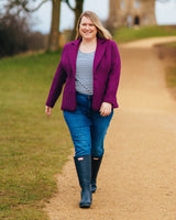 Woman in a purple coat, striped shirt, and blue jeans walking on a path outdoors.. This blazer is the Auburn Blazer sewing pattern from Cashmerette.