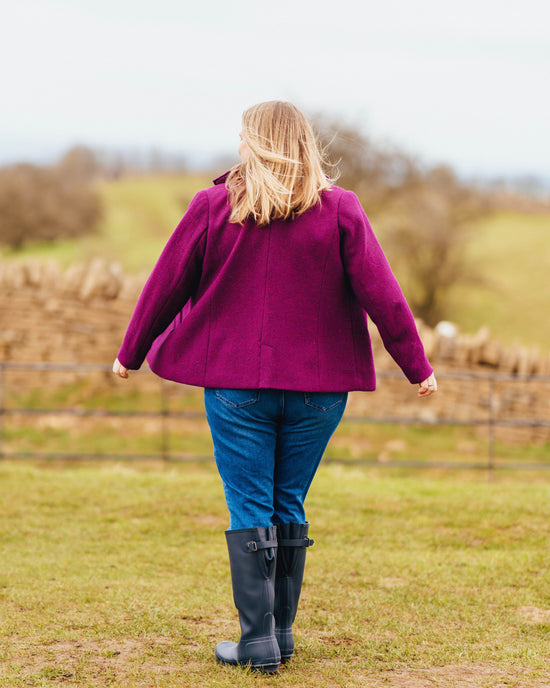 Person wearing a purple coat and blue jeans standing in a field. This blazer is the Auburn Blazer sewing pattern from Cashmerette.