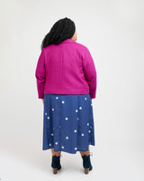 Person wearing a pink jacket and blue polka dot dress on a white background. This blazer is the Auburn Blazer sewing pattern from Cashmerette.