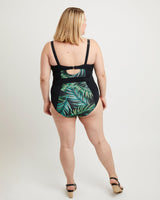 Woman wearing a black swimsuit with green leaf pattern on a white background. This swimsuit is the Ipswich Swimsuit sewing pattern from Cashmerette.