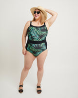 Woman wearing a tropical leaf print swimsuit with a white background. This swimsuit is the Ipswich Swimsuit sewing pattern from Cashmerette.