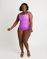 Woman wearing a purple swimsuit on a white background. This swimsuit is the Ipswich Swimsuit sewing pattern from Cashmerette.