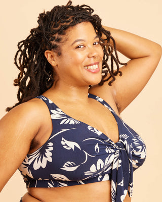Woman wearing a navy blue floral patterned top against a beige background. This swimsuit is the Marblehead Swimsuit sewing pattern from Cashmerette.