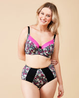 Woman wearing a floral lingerie set on a beige background. This bra is the Willowdale Bra sewing pattern from Cashmerette.