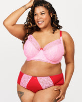 Woman wearing a pink and red lingerie set on a white background. This bra is the Willowdale Bra sewing pattern from Cashmerette.