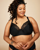 Woman wearing a black lace bra against a beige background. This bra is the Willowdale Bra sewing pattern from Cashmerette.