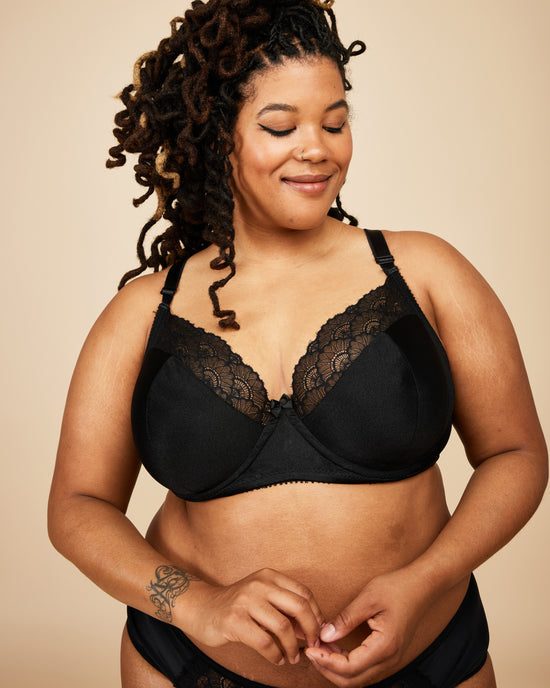 Woman wearing a black lace bra against a beige background. This bra is the Willowdale Bra sewing pattern from Cashmerette.